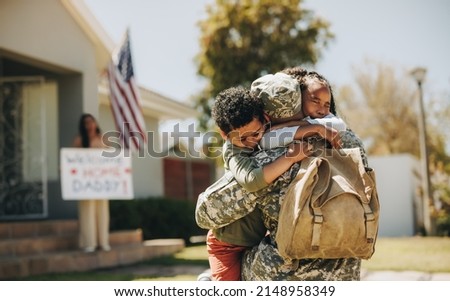 Emotional family reunion. Military dad embracing his children after returning home from the army. American soldier receiving a warm welcome from his family after serving in the military. Royalty-Free Stock Photo #2148958349