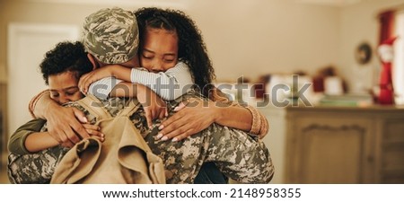 Soldier embracing his wife and kids on his homecoming. Serviceman receiving a warm welcome from his family after returning from deployment. Military family having an emotional reunion. Royalty-Free Stock Photo #2148958355