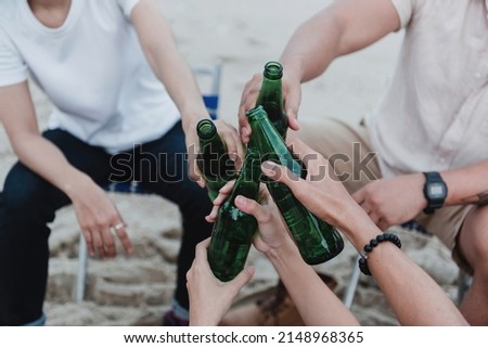 hands holding beverage bottles and touching each other at a party.