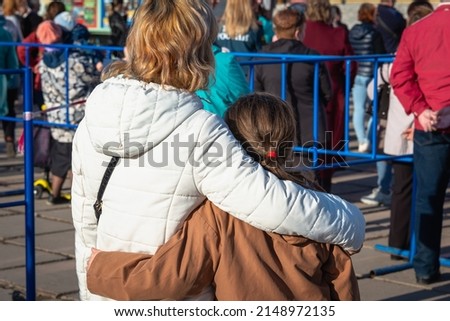 A girl with her mother watch the concert in an embrace. Meeting.