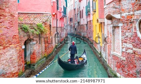 Venetian gondolier punting gondola through green canal waters of Venice Italy Royalty-Free Stock Photo #2148987971