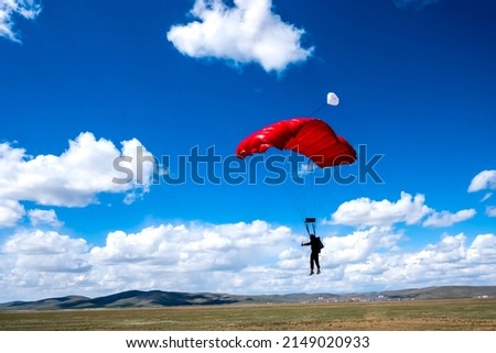 Skydiving parachutist about to land Royalty-Free Stock Photo #2149020933