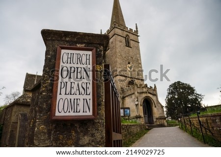 welcome sign by path leading up to the front of 14th Century St Cyriac's Church in Lacock village, Wiltshire UK