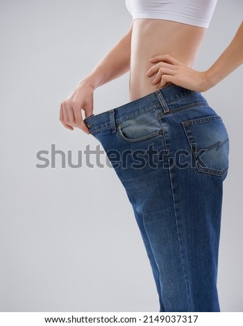 You can achieve this too. Cropped shot of a woman showing off her weightloss with a large pair of trousers. Royalty-Free Stock Photo #2149037317