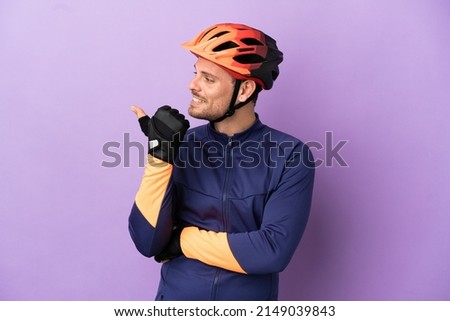 Young Brazilian cyclist man isolated on purple background pointing to the side to present a product Royalty-Free Stock Photo #2149039843