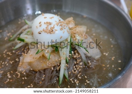 Naengmyeon is a noodle dish of Korean origin which consists of long and thin handmade noodles made from the flour and starch of various ingredients, including buckwheat. Royalty-Free Stock Photo #2149058211