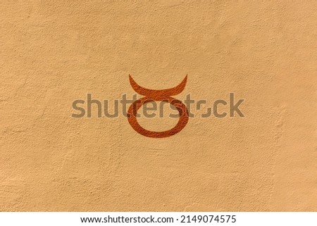 shot of a zodiac sign drawn on a yellow wall, the specific sign is Taurus