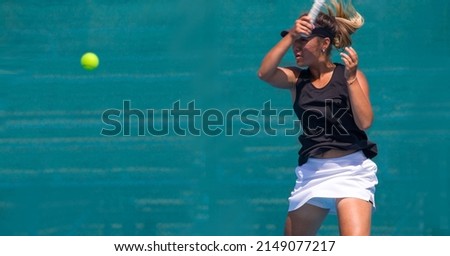 A girl plays tennis on a court with a hard blue surface on a summer sunny day
 Royalty-Free Stock Photo #2149077217