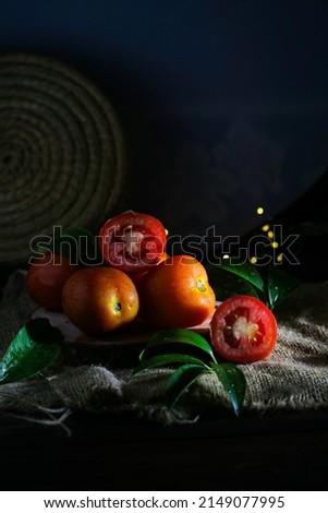 a collection of whole and sliced ​​tomatoes served on a burlap mat, darkmood, vegetable still life