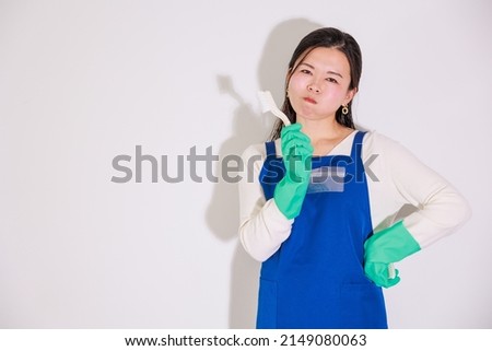 Japanese woman wearing rubber gloves and holding cleaning tools