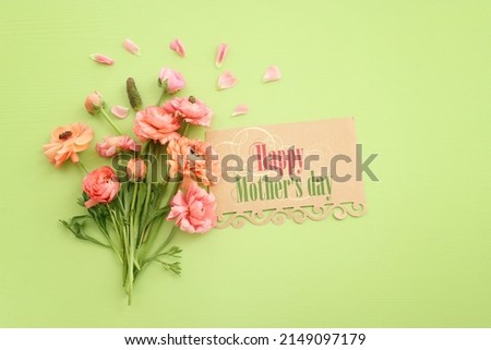 mother's day concept with pink flowers over green wooden background