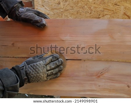 cleaning the surface of wooden furniture by hand using sandpaper, black-gloved hands hold the sandpaper and smooth the wood of the product, finishing the wood during the production process Royalty-Free Stock Photo #2149098901