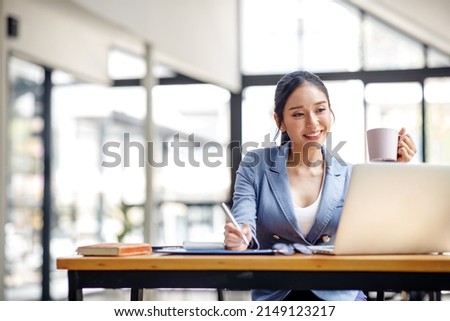 Asian Businesswoman Using laptop computer and working at office with calculator document on desk, doing planning analyzing the financial report, business plan investment, finance analysis concept. Royalty-Free Stock Photo #2149123217