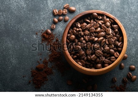 Coffee beans background. Roasted Coffee beans in wooden bamboo bowl on dark black stone background. Top view. Coffee concept. Mock up.