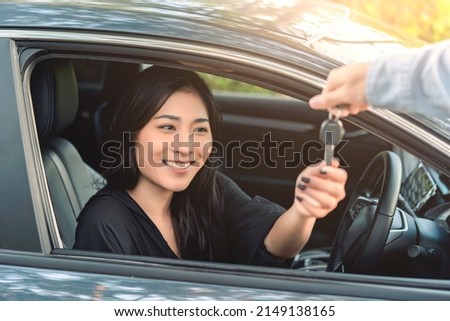Asian woman buying or renting rental new car owner receiving car key from sales seller, taking and passing driving license examination test, happy cheerful smiling excited salesman sold car dealership