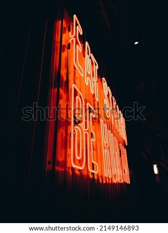 Red neon light lettering "Eat steaks Be human" in dark, vertical photo