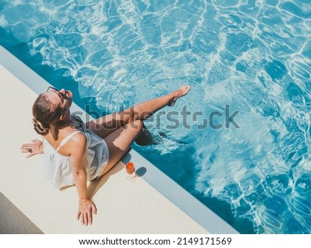 Fashionable woman sitting by the pool on the empty deck of a cruise liner. Closeup, outdoor, view from above. Vacation and travel concept