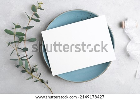 Wedding stationery invitation card mockup 7x5 on grey background with eucalyptus, Menu card mockup with festive wedding or birthday table setting, blue ceramic plate. Minimal blank card mockup