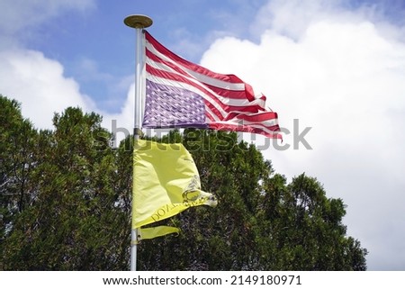 American Flag upside down flying on a metal pole with trees in background.                              