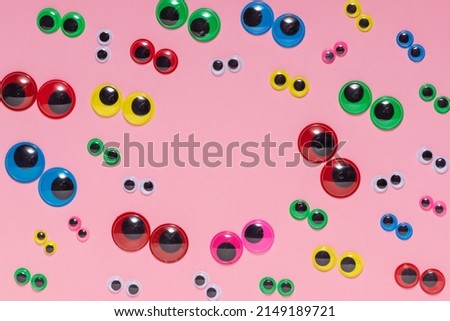 Multicolored plastic eyes on a pink background. Googly eyes.