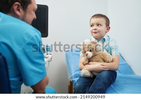 Caucasian young boy sitting with toy in doctor office