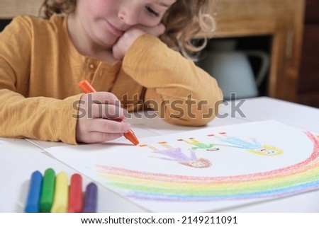 Thoughtful child drawing LGBT family with crayons