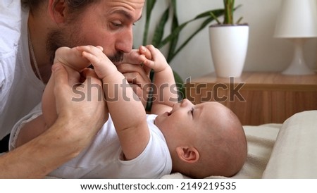 Authentic Young Bearded Man Holding Newborn Baby. Dad And Child Son On Bed. Close-up Portrait of Smiling Family With Infant On Hands. Happy Marriage Couple On Background. Childhood, Parenthood Concept Royalty-Free Stock Photo #2149219535