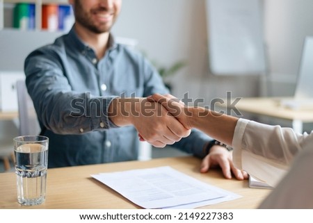Cropped view of human resources manager shaking hands with successful vacancy applicant at office, closeup. Unrecognizable headhunting specialist welcoming new employee into company team Royalty-Free Stock Photo #2149227383