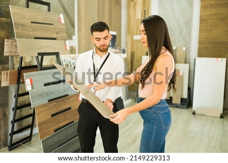 Gorgeous hispanic woman choosing new floors for her house. Salesperson speaking with a client about buying floors at the furniture store Royalty-Free Stock Photo #2149229313