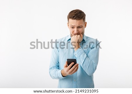 Portrait of a man in a desperate situation. The man looks at the smartphone, extremely confused and alarmed because of the failure. Royalty-Free Stock Photo #2149231095