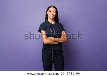 Portrait of a beautiful hispanic doctor smiling and looking at the camera while standing in front of a purple background