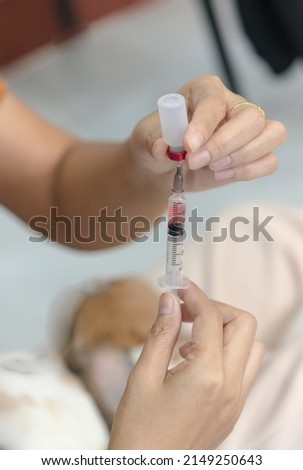 Nurse's hand draws solution into syringe from vial in clinic office.