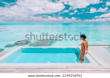 Luxury resort travel vacation destination idyllic overwater bungalow villa woman relaxing by infinity pool. Social media influencer traveler luxurious high end lifestyle. Royalty-Free Stock Photo #2149256953