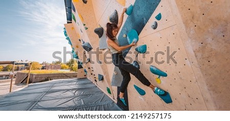 Bouldering climbing athlete woman training strength at outdoor gym boulder climb wall. Asian fit girl going up having fun in extreme sport hobby. Banner panoramic Royalty-Free Stock Photo #2149257175