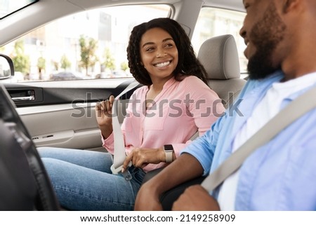 Smiling African Amerfican man and woman fastening seat belts after get in the brand new car, happy black lovers having weekend trip together, ready for vacation, driving modern auto. Safety Fist Royalty-Free Stock Photo #2149258909
