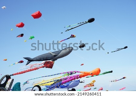 Various kites flying on the blue sky in the kite festival. Royalty-Free Stock Photo #2149260411