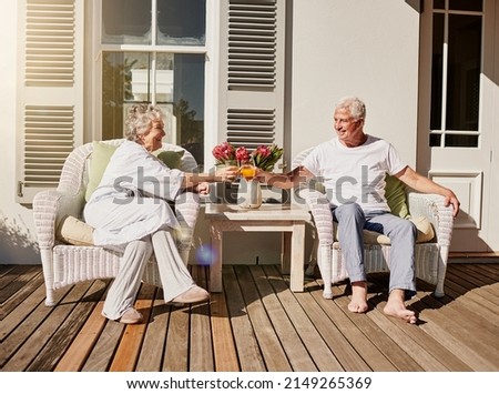 Heres to more mornings like this. Shot of a happy senior couple toasting with juice on the patio at home.