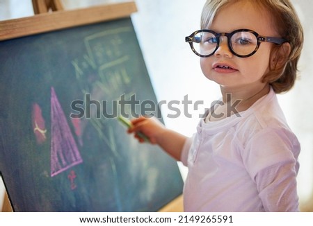 Making mathematics look like childs play. Portrait of an adorable little girl with big spectacles solving a math problem on a chalkboard at home.