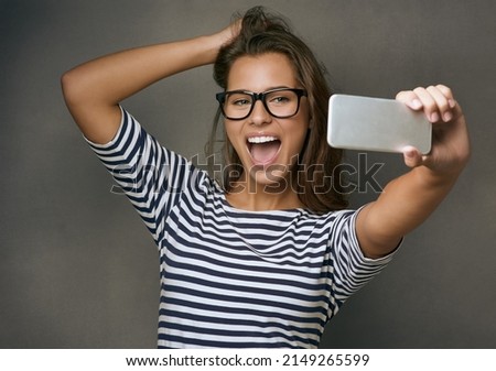 Happiness is taking a perfect selfie on the first try. Studio shot of an attractive young woman taking a selfie against a grey background.