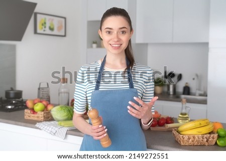 Female food blogger in blue apron recording video blog about cooking