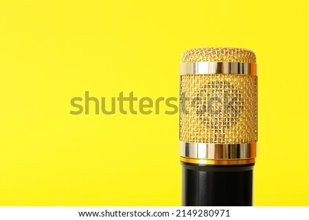 Modern microphone on yellow background, closeup