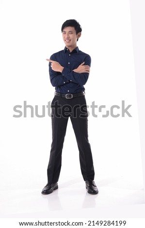 Full body 
portrait of young man in blue shirt with finger to side standing posing white background
