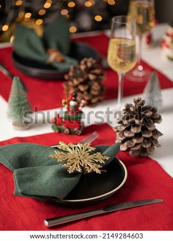 Christmas table holiday serving with linen towels and kitchen ware. Snowman figures and sparkling wine, spruce cone.