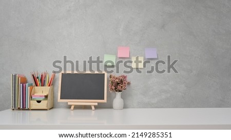 Stationery, potted plant and empty chalkboard on white table. Copy space for your information content.