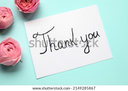 Sheet of paper with text THANK YOU and flowers on blue background