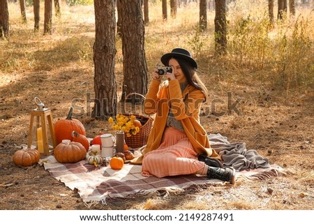Young woman taking photo during romantic picnic in forest