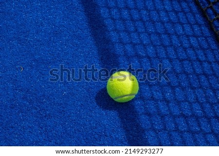 Ball in the shade of the net of a blue paddle tennis court. Royalty-Free Stock Photo #2149293277