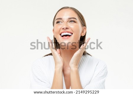 Optimistic female with clean face skin looking away with smile on white background with raised hands in light studio Royalty-Free Stock Photo #2149295229