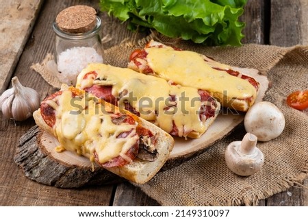 Italian sandwich pizza with mushrooms, sausages and cheese on a wooden table.