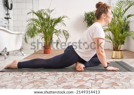 Young woman going yoga exercise at home. Health care online lessons. Indoor fitness workout. Remote sport trainer. Morning activity. Floor pilates mat. Female person lifestyle. Asana pose Royalty-Free Stock Photo #2149314413